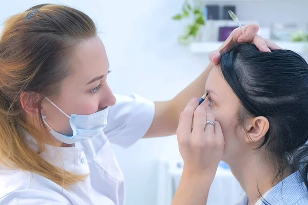 Cosmetoloog schilderen wenkbrauwen voor client vrouw voor microblading procedure. — Stockfoto