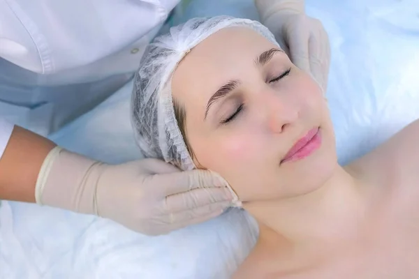 Cosmetologist limpa o rosto das mulheres com almofadas de algodão na clínica de beleza, close-up. — Fotografia de Stock