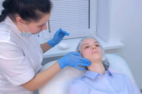 Cosmetoloog aanbrengen van genezing crème na injecties biorevitalisatie op het gezicht. — Stockfoto