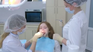 Dişçi ortodontist, kameraman kız dişlerini kullanarak bunu aynada gösteriyor..