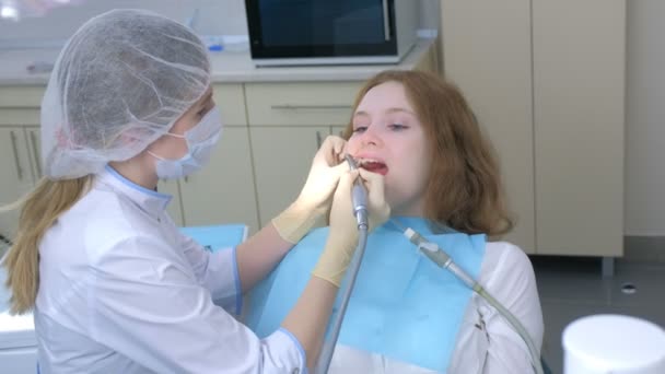 Stomatolog čistí dívčí zuby elektrickým zubním kartáčkem v zubním lékařství. — Stock video