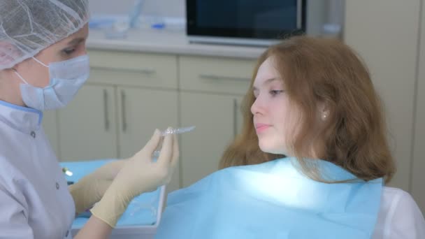 Médico ortodoncista instalando frenos transparentes de silicona en los dientes de las niñas. — Vídeo de stock