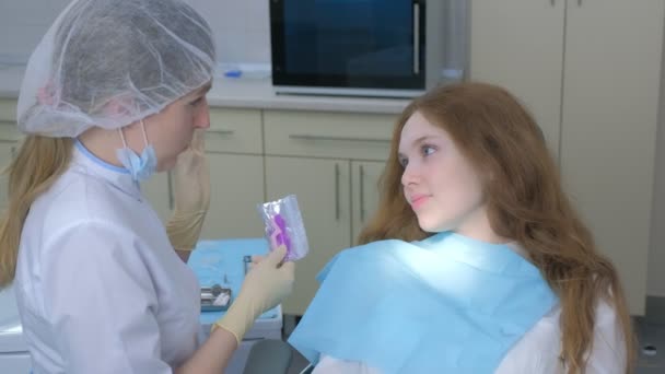 Médico ortodoncista explicar chica cómo cuidar de los aparatos ortopédicos de silicona en la odontología. — Vídeo de stock