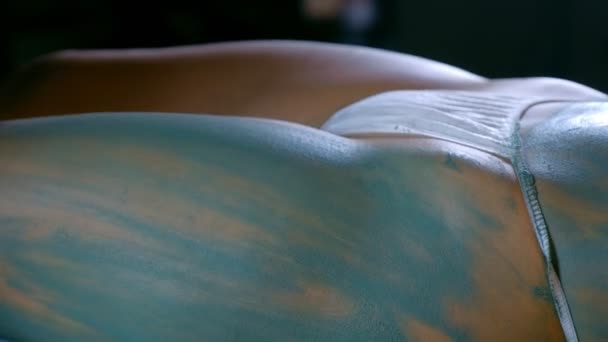 美容师男人用蓝色黏土贴在女人的腿上，用特写双手. — 图库视频影像