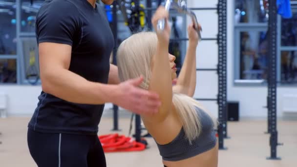 Mujer deportiva con entrenador haciendo ejercicio para los músculos de los brazos en la máquina de entrenamiento. — Vídeo de stock