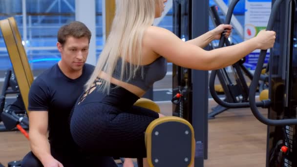 Sportliche Frau mit Trainer macht Übungen für Beine, Beute auf dem Trainingsgerät. — Stockvideo