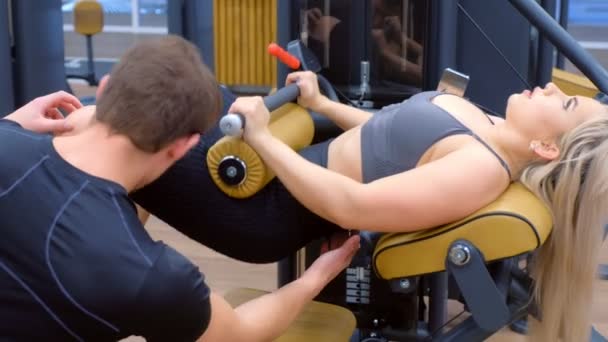 Mujer deportiva con entrenador haciendo ejercicio para el botín en la máquina de entrenamiento. — Vídeos de Stock