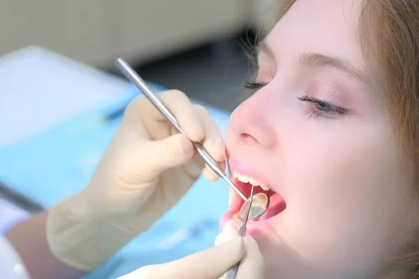 Orthodontiste dentiste examine les dents des filles à l'aide d'outils dentaires aiguille et miroir. — Photo