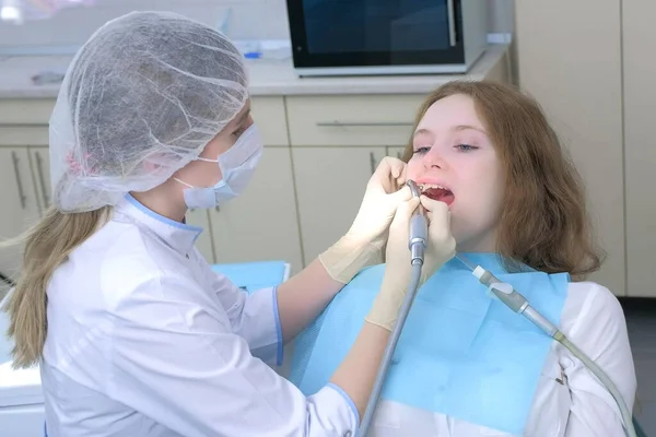 Stomatologe reinigt Zähne von Mädchen mit elektrischer Zahnbürste in der Zahnmedizin. — Stockfoto