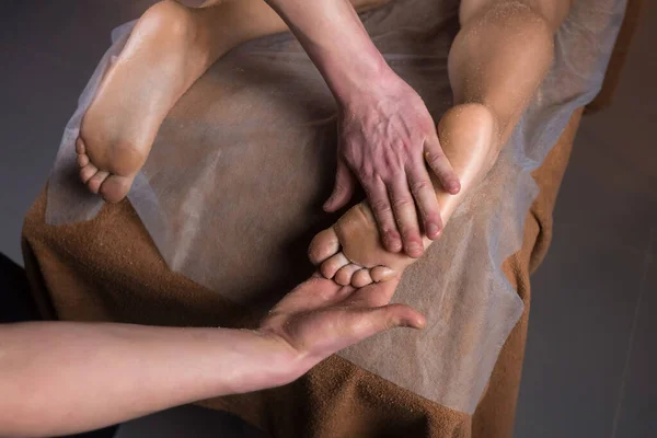 Massagista esfregando mulheres pés com esfoliação natural no salão de spa descascando corpo. — Fotografia de Stock