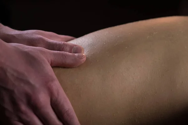 Massagista esfregando as pernas da mulher esfoliação natural no salão de spa descascando corpo, close-up. — Fotografia de Stock