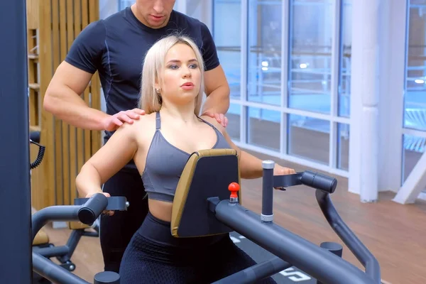 Mujer deportiva está haciendo ejercicios para los músculos de la columna vertebral en simulador de remo bloque. —  Fotos de Stock