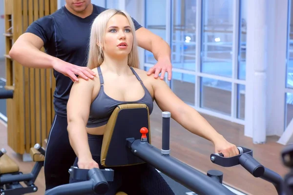 Mujer deportiva está haciendo ejercicios para los músculos de la columna vertebral en la máquina de remo bloque. —  Fotos de Stock