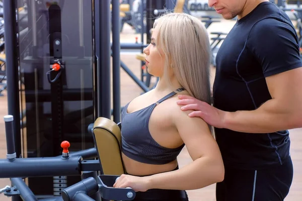 Mujer deportiva está haciendo ejercicios para los músculos de la columna vertebral en la máquina de remo bloque. —  Fotos de Stock