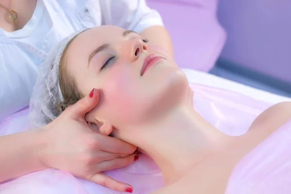 Cosmetologist massagist doctor makes myoplastic neck massage to young woman. Stock Picture