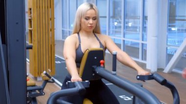 Sportif kadın kürek çekme simülatöründe omurga kasları için egzersiz yapıyor..