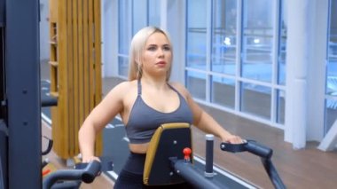 Sportif kadın kürek çekme makinesinde omurga kasları için egzersiz yapıyor..