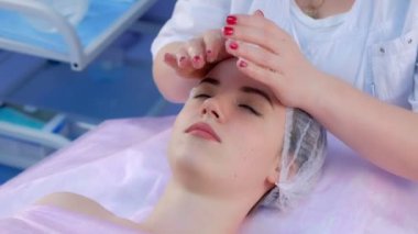 Güzellik uzmanı yüz masajı yapmadan önce kızların yüzüne krem sürüyor..