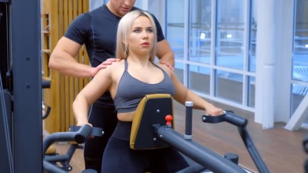 Mujer deportiva está haciendo ejercicios para los músculos de la columna vertebral en la máquina de remo bloque. — Vídeos de Stock