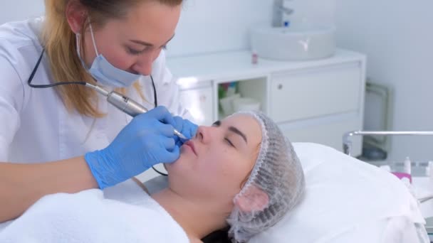 Cosmetologist making lips microblading procedure for girl using tattoo machine. — Stock Video