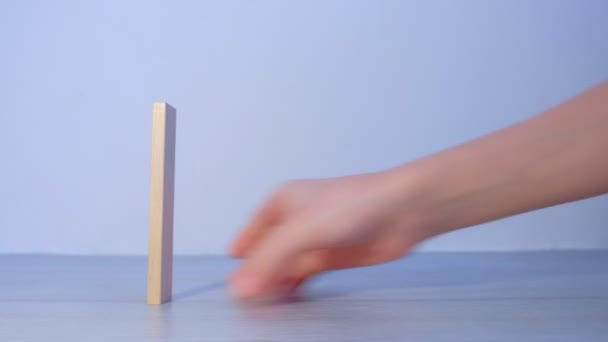 Mans hand bouwt van houten blokken als dominos en vernietigt het duwen van een. — Stockvideo