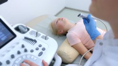 Hasta çocuk tiroid bezini ultrason tarayıcı kullanarak muayene eden doktor..