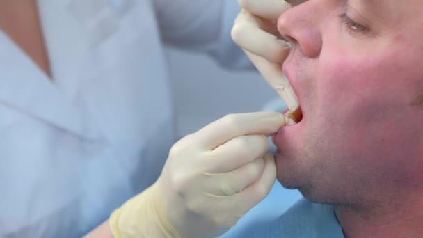 Mujer dentista está enseñando al hombre a limpiar los dientes con hilo dental, primer plano. — Vídeos de Stock