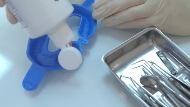 Dentista coloca gel de flúor no protetor bucal na clínica de estomatologia, mãos fechadas. — Vídeo de Stock