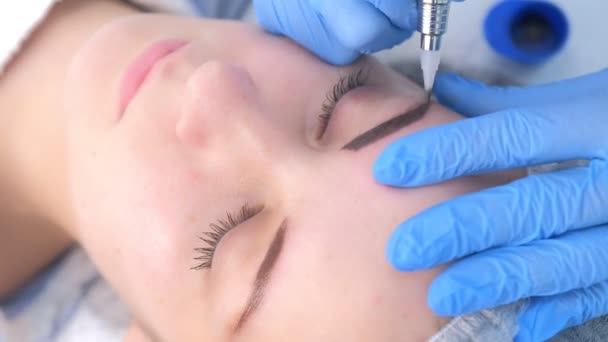 Cosmetologist making eyebrows microblading procedure in beauty salon for girl. — Stock Video