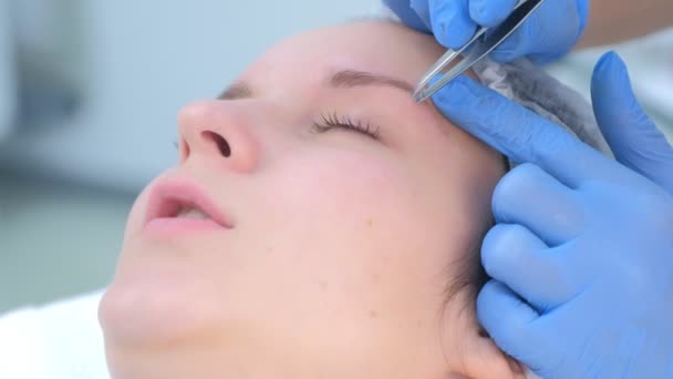 Esteticista arranca el pelo en las cejas con pinzas para mujer, primer plano de la cara. — Vídeos de Stock