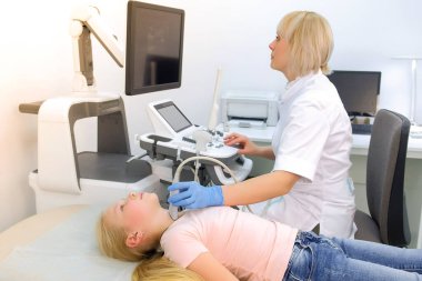 Hasta çocuk tiroid bezini ultrason tarayıcı kullanarak muayene eden doktor..