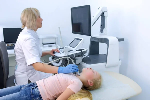 Doctor examining patient child girl thyroid gland using ultrasound scanner.