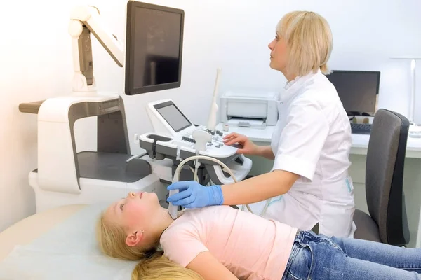 Doctor examining patient child girl thyroid gland using ultrasound scanner. Royalty Free Stock Images