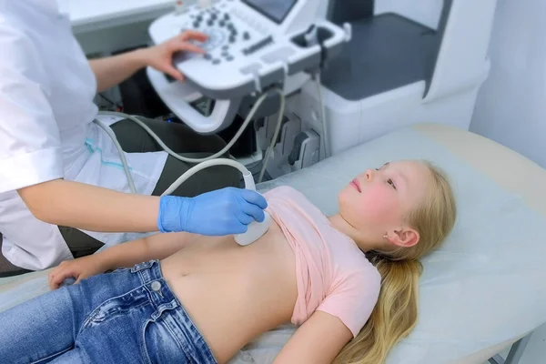 Doctor making abdominal ultrasound of internal organs child girl using scanner. Stock Photo