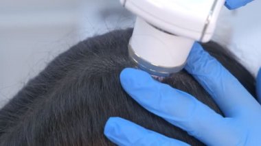 Doktor trichologist klinikte dermatoskop kullanan kadın hasta kıllarını inceliyor..