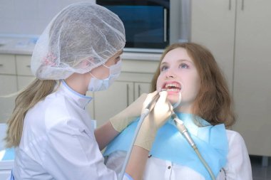 Ortodontist kadın dişlerine özel jel sürüyor ve dişçilikte kurutuyor..