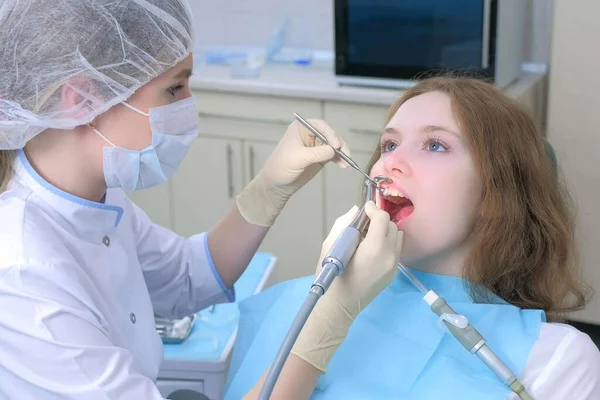 Dentist woman cleaning girls teeth using electric toothbrush in dentistry.