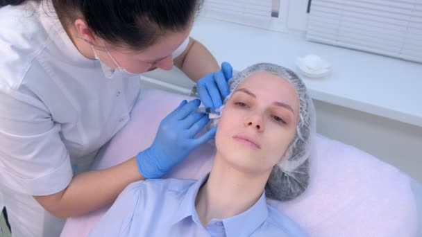 Косметолог, який робить декілька ін'єкцій біоревіталізації в шкірі обличчя жінки . — стокове відео