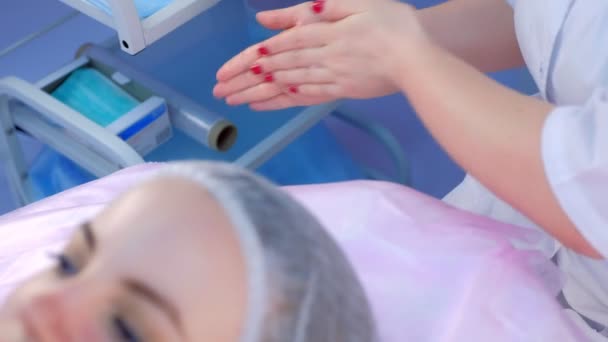 美容師の医師は、診療所でマッサージをする前に手を暖めてこすり. — ストック動画