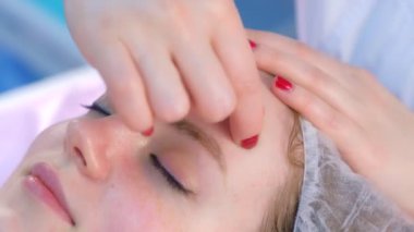 Güzellik doktoru güzellik kliniğindeki kadına miyoplastik yüz masajı yapıyor..