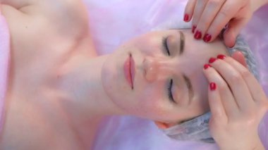 Kozmetik doktoru güzellik kliniğinde kadınlara miyoplastik yüz masajı yapıyor..