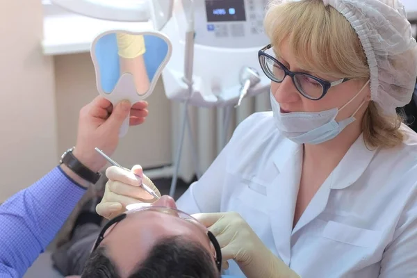 Dentista que muestra defectos en los dientes del paciente usando gel azul y aguja en odontología. — Foto de Stock