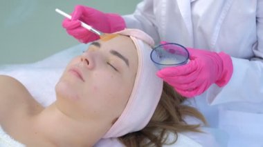 Kozmetik doktoru, güzellik kliniğinde fırça kullanarak kadınların yüzüne maske takıyor..