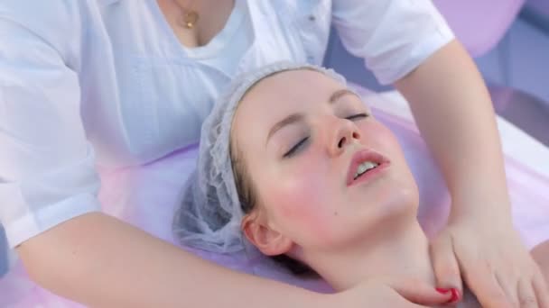 Kosmetolog wyciera kobietom szyję i twarz podkładkami bawełnianymi w klinice kosmetycznej. — Wideo stockowe