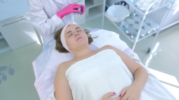 Kosmetikerin trägt in Klinik Peeling-Lotion auf Frauengesicht mit Pinsel auf. — Stockvideo