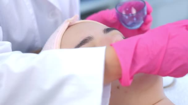 Dokter Beautician mengoleskan lotion mengupas pada wajah wanita menggunakan kuas di klinik. — Stok Video