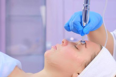 Genç kadın için Hyaluronic asit jeli ile mikro akım yüz tedavisi, yakın çekim.