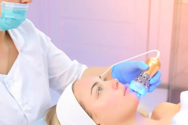 Cosmetoloog arts die fonoforese procedure op vrouw gezicht in kliniek. — Stockfoto
