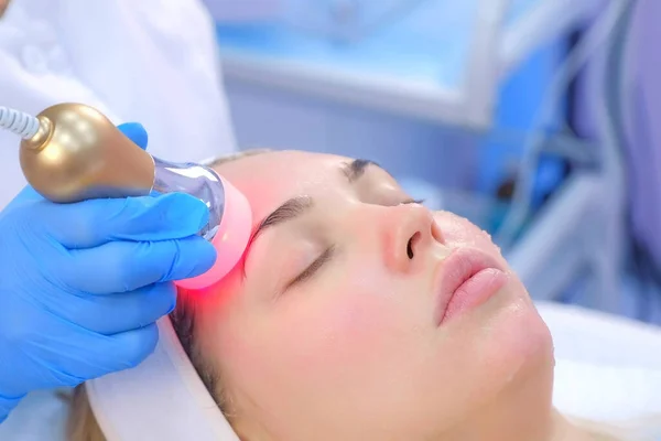 Cosmetoloog arts die fonoforese procedure op het gezicht van de vrouw, zijaanzicht. — Stockfoto