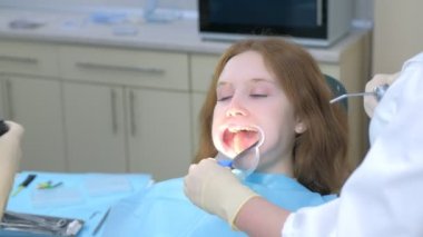 Dişçi ortodontist, kameraman kız dişlerini kullanarak bunu aynada gösteriyor..